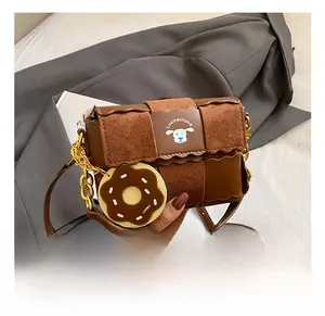 Close-up of brown woven square bag with gold chain strap and donut charm detail