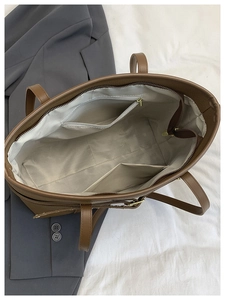 Detailed interior of a brown tote bag showing zipper pockets and spacious structure