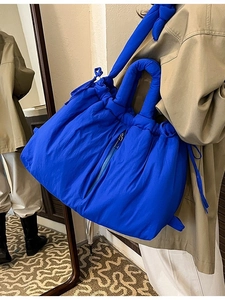 Quilted blue puffer tote bag with padded handles and crossbody strap for winter style