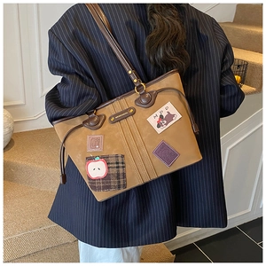 Vue détaillée du sac cabas marron vintage avec écussons créatifs et poignées en cuir