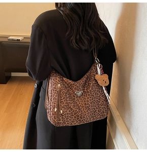 Detail view of leopard print hobo bag with teddy bear charm and ribbon on model