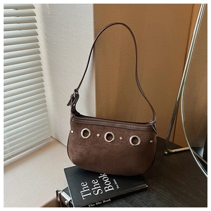 Detail of dark brown suede handbag featuring three metallic ring rivets and leather strap