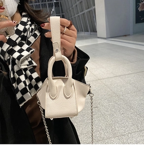 Detail of white mini bucket bag in pebble leather with silver chain and metal feet