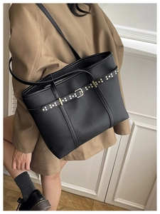 Detail of black pebbled leather tote bag with gold metal hardware and rivet accents
