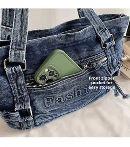 Detail of denim tote bag showing front zipper pocket with phone storage and embroidery