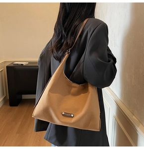 Macro detail of camel wool tote bag with brand plaque and dark brown leather strap