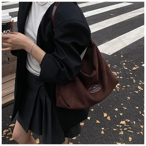 Deep brown suede shoulder bag featuring a premium oval leather logo patch detail