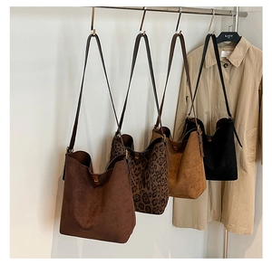Dettaglio di borse tote in camoscio con stampa leopardata appese a un supporto metallico