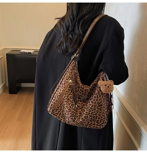 Detail of leopard print hobo bag with adjustable brown strap and plush bear charm