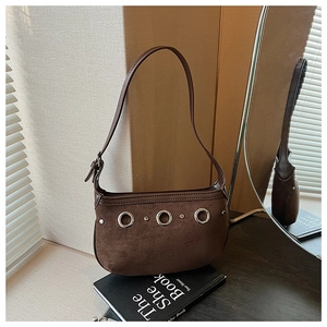 Detailed view of dark brown suede underarm bag with silver metal eyelets and rivets