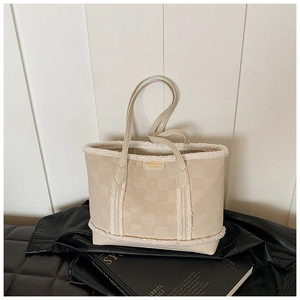 Detail of beige tote bag with white plush trim and embossed clover patterns