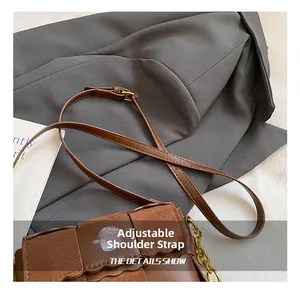 Detail view of the adjustable leather strap and gold chain on this brown shoulder bag