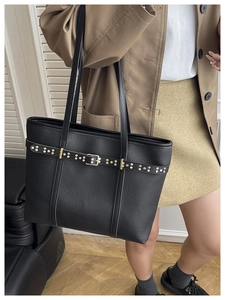 Close-up of black lychee grain leather tote bag with gold studs and buckle detail