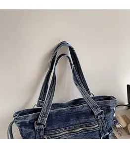 Detail of reinforced denim straps with vintage metal rings on a navy blue tote bag