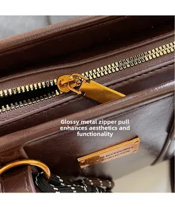 Detailed macro view of dark brown leather bag with golden zipper and metal logo plate