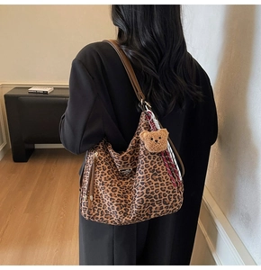 Close-up of leopard print tote bag with brown leather strap and plush bear charm