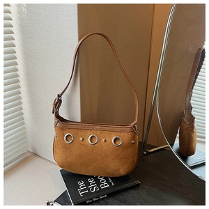 Close-up of brown suede shoulder bag with silver metal rings and stud decorative details