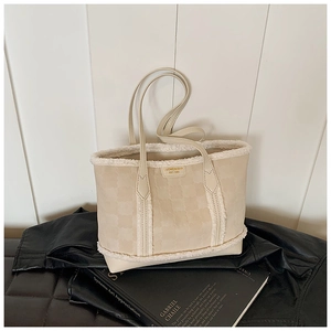 Detail of beige tote bag with clover embossing and white faux fur trim on black leather