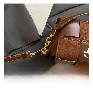 Detail of brown woven leather texture with gold metal chain and snap hook
