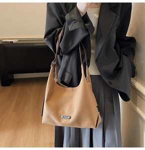 Detail of light brown matte shoulder bag with slim straps worn over a grey blazer