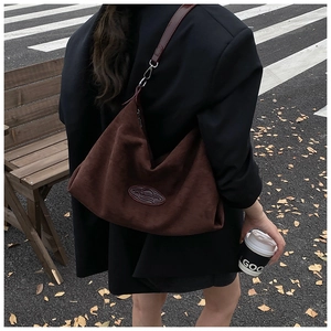 Detailed macro view of dark brown suede tote bag with leather straps and silver buckle
