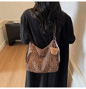 Leopard print hobo bag with teddy bear charm and red ribbon detail on a model back