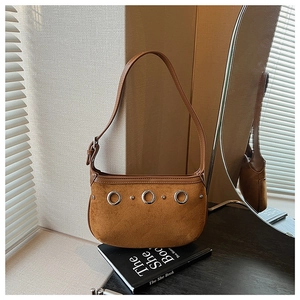 Close-up of brown suede shoulder bag with silver rings and adjustable strap buckle