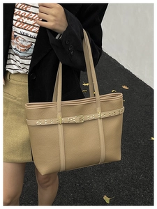 Outdoor shot of khaki leather tote bag with rivet buckles and golden hardware finish
