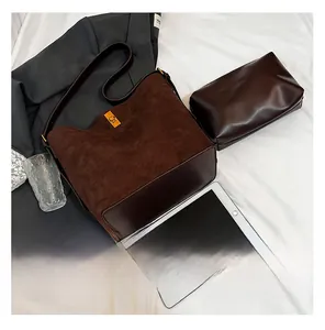 Dettaglio della grande borsa a secchiello in camoscio marrone con fibbia dorata e bustina