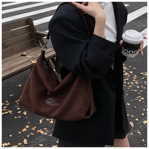 Close-up of deep brown suede shoulder bag showing large capacity and brand logo patch