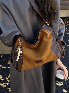 Suede and leather patchwork tote bag with wooden beads in an autumn street setting