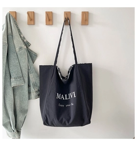 Borsa tote nera minimalista appesa a un gancio di legno con giacca di jeans decorativa