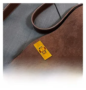 Dettaglio borsa tote in pelle scamosciata marrone scuro con chiusura a scatto in metallo oro