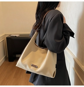 Detail of beige canvas shoulder bag with brown leather trim and Ruitaijia logo
