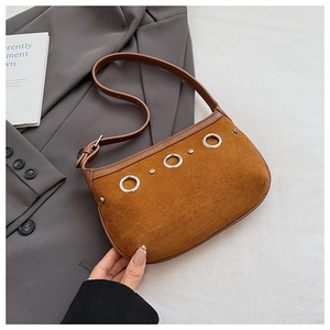 Detail of brown suede tote with silver eyelets and adjustable strap on grey blazer