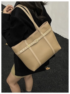 Close-up of khaki litchi grain leather tote bag with gold rivets on model shoulder