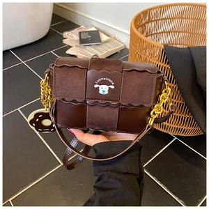 Détail du sac bandoulière marron foncé avec chaîne dorée et breloque doughnut