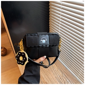 Détail du sac oreiller tissé noir avec bord ondulé et bandoulière chaîne dorée