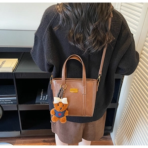 Detail of vintage brown tote bag with adjustable strap and cute plush bear charm