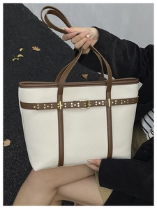 Detail of off-white lychee leather tote bag with brown contrast straps and gold rivets