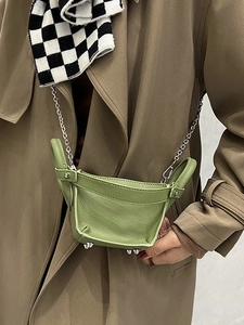 Avocado green small bucket bag with chain strap shown on model in a stylish coat