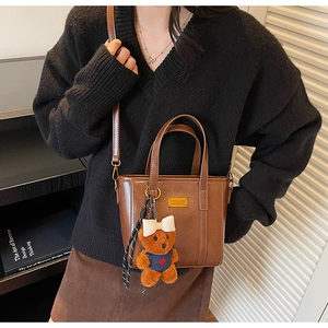 Brown leather crossbody bucket bag with adjustable strap and cute teddy bear charm