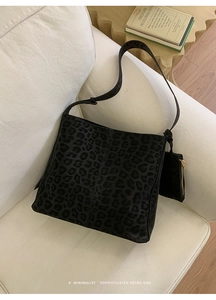 Detail of leopard print bucket bag with matching mini pouch on a white cozy sofa