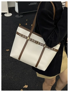 Lifestyle shot of large cream tote bag with brown trim and gold buckle details