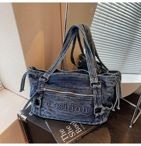 Detail of blue denim tote bag with Fashion embroidery and silver zipper pocket