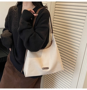 Detail view of cream leather underarm bag with a brown shoulder strap and metal logo