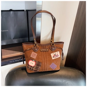 Détail du grand sac cabas en daim marron avec écusson chien et anses en cuir souple
