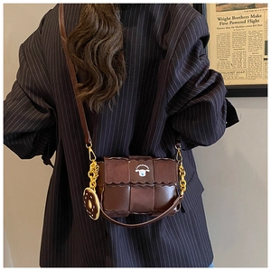 Sac oreiller marron tissé avec pendentif donut et chaîne porté à l'épaule par un mannequin