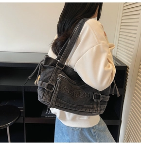 Detail of grey denim tote bag with adjustable straps and Fashion embossed lettering