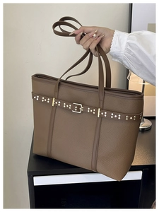 Detailed macro view of brown leather bucket bag with litchi grain and gold studs